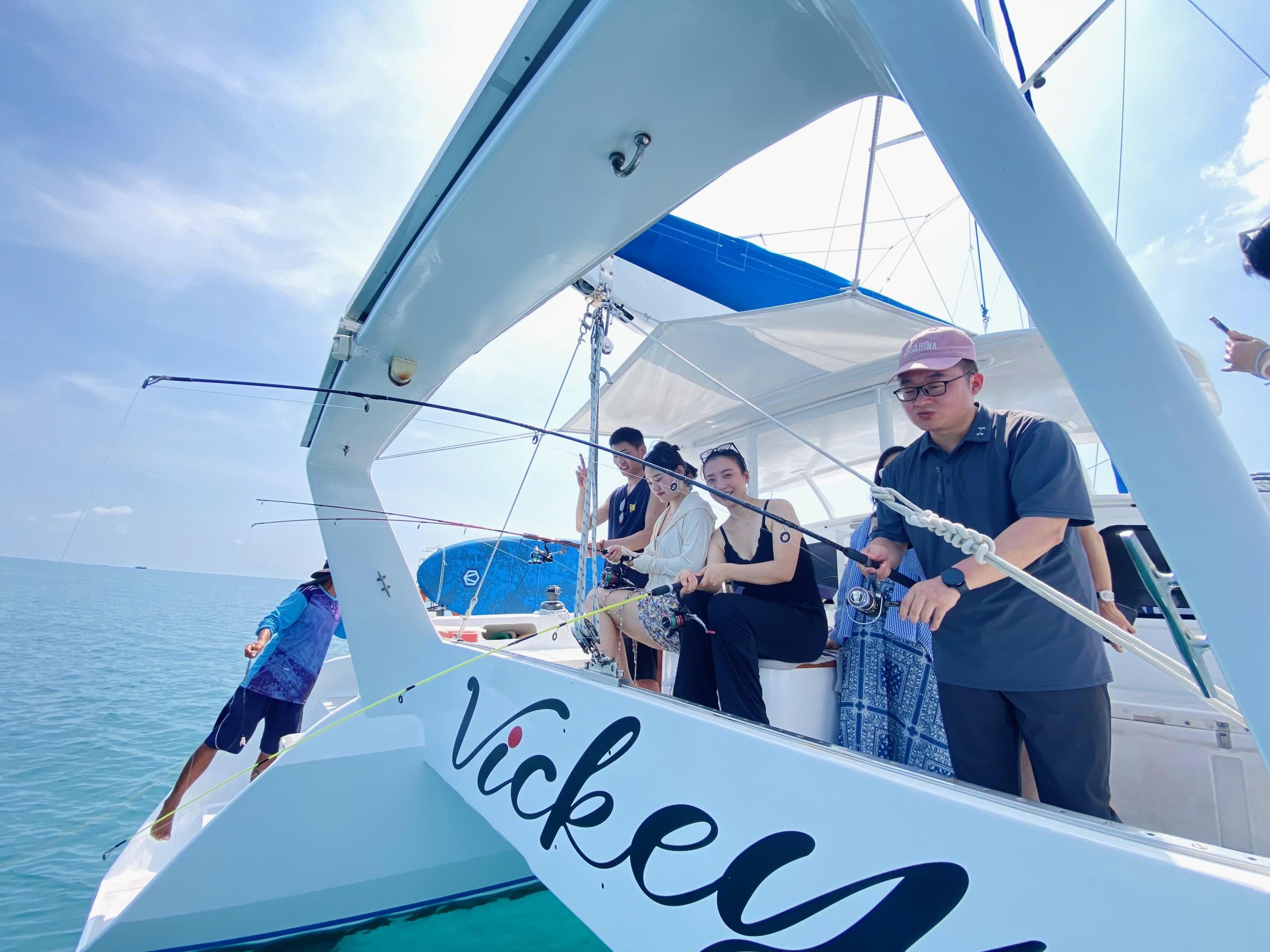Group of people fishing on white catamaran "Vickey" in clear blue sea